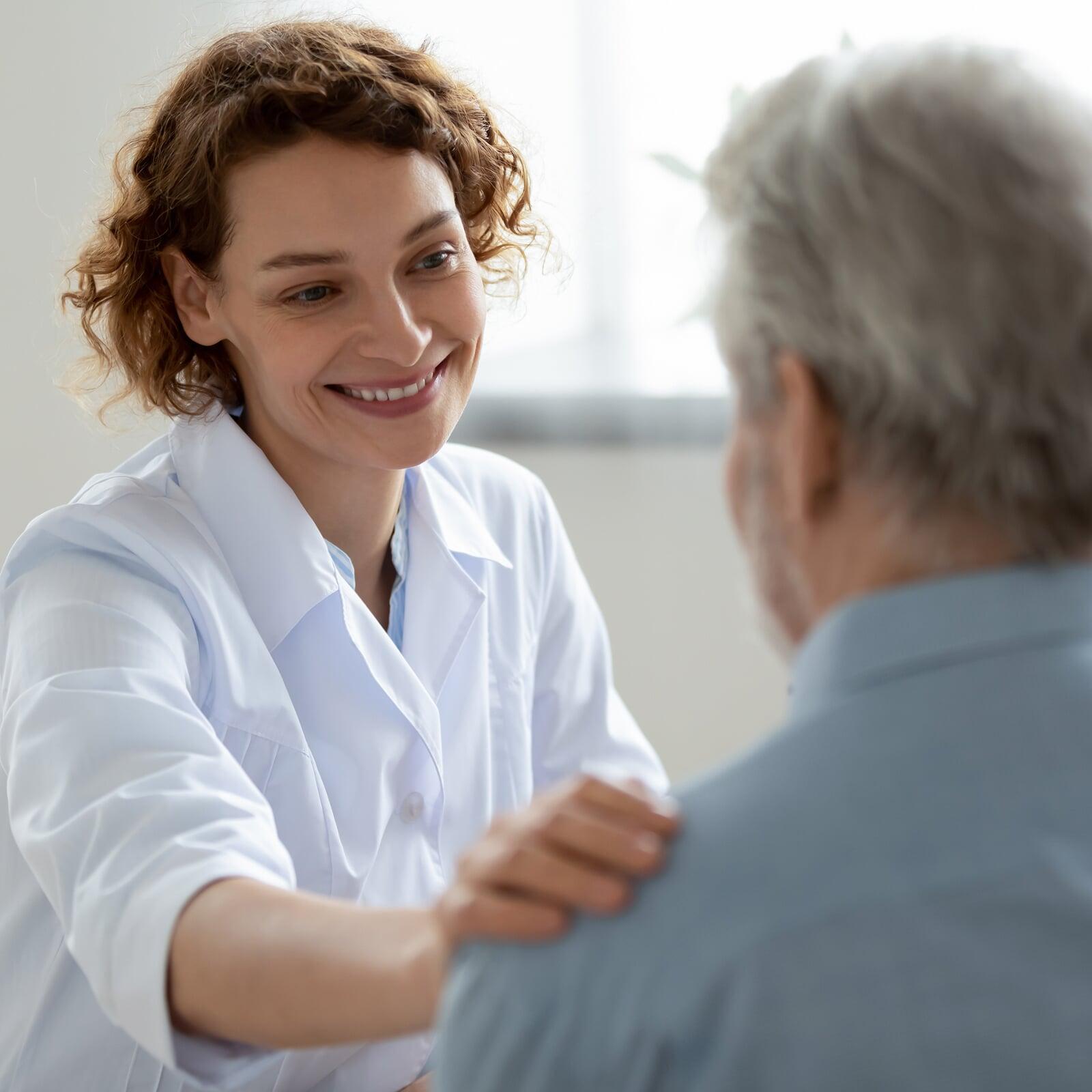 Lächelnde Beraterin legt Patient Hand auf die Schulter in Nahaufnahme
