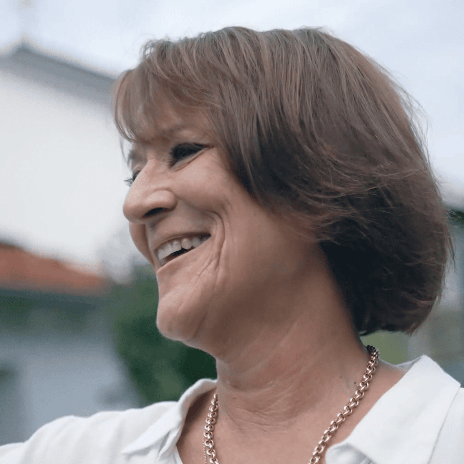 Lachende Frau ohne Brille in Portraitformat.